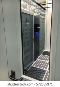 Abstract Of Modern High Tech Internet Data Center Room With Rows Of Racks With Network And Server Hardware. View Through The Window Of The Door