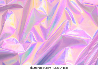 Abstract Modern pastel colored pink holographic background in 80s style. Crumpled iridescent foil textile real texture. Synthwave. Vaporwave style. Retrowave, retro futurism, webpunk