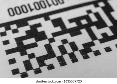Abstract monochrome close up of isolated printed QR data matrix bar code on white paper label background from material inventory tracking system