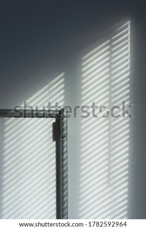 Abstract of morning light and shadow on wall through window blind shutter.  Light through blinds window. Parallel lines of light and reflection provide