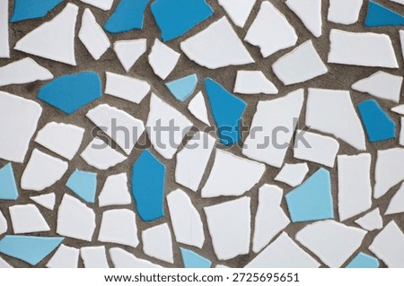 Abstract mosaic pattern with broken white and blue tiles.
