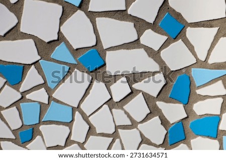 Abstract mosaic pattern with broken white and blue tiles.