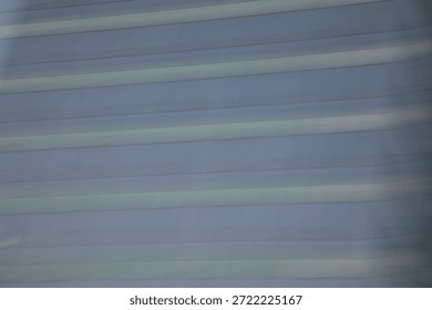 Abstract motion blur background created by intentional camera movement of a modern skyscraper facade. The image features smooth, horizontal streaks of blue, grey, and white, resembling a digital texture or futuristic speed lines. Minimalist architectural art suitable for corporate, technology, or business design backdrops.