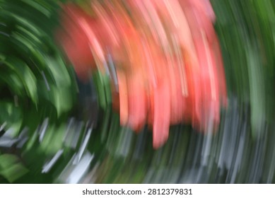 Abstract motion blur background of red flowers and green leaves, intentional camera movement panning effect creating a dynamic natural texture.
