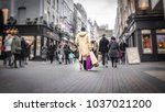 Abstract motion blurred shopper carrying shopping bags on crowded London street 