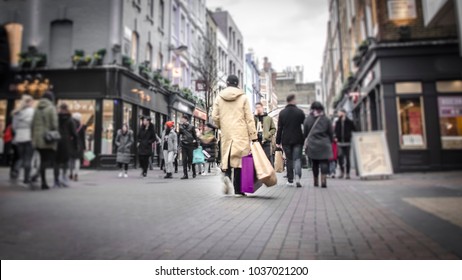 Abstract Motion Blurred Shopper Carrying Shopping Bags On Crowded London Street 