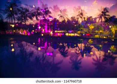 Abstract Multiple-exposure Defocused View At Dusk Of Palm Trees And Neon Lights Of Ocean Drive Reflecting In Puddle At Dusk In South Beach, Miami, Florida, USA