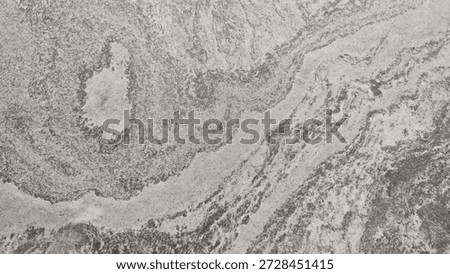 An abstract natural stone surface texture with a pattern of flowing grey and white veins. Ideal for use as a background, material for interior design, countertops, or architectural surfaces.