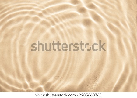 Abstract nature textured background, water waves in the pool with sun reflection. Clear water with bubbles and circles on beige background