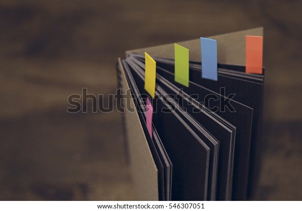 Abstract\
notebook with color note tab. Notebook with colors note tab on\
wooden table background, Vintage picture\
tone.\
