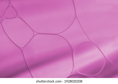 Abstract Oil and water droplets with light effect on pink-purple colour.