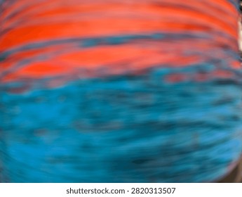 An abstract, out-of-focus background featuring horizontal bands of vibrant orange and deep blue colors blending together.