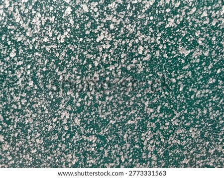 Abstract paint splatter texture on a teal green metal surface. Abstract background with white paint splatters on a dark green background.
