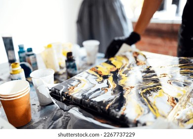 Abstract painting is made in the technique of painting with liquid acrylic. Acrylic Fluid Pouring. Fluid Art. Beautiful smooth lines and paint transitions. White, gold, mint, black colors background.