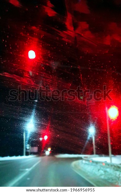 Abstract painting, red lights of a\
traffic light at night through a blurred windshield of a\
car