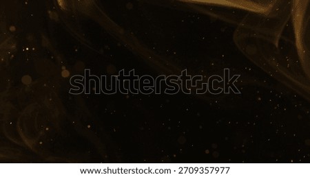 Abstract particles of gold dust float in the air, isolated against a black background with a warm yellow glow, creating a dreamy and cinematic atmosphere.
