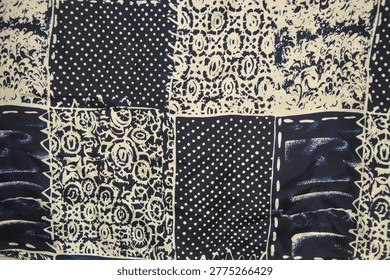 Abstract patchwork textile pattern in navy blue and off-white. Close up of fabric texture with polka dots, floral ornaments, and batik motifs for vintage background.