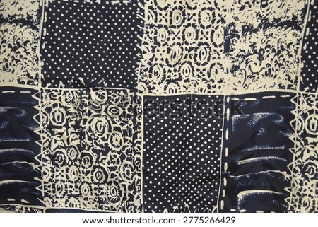 Abstract patchwork textile pattern in navy blue and off-white. Close up of fabric texture with polka dots, floral ornaments, and batik motifs for vintage background.