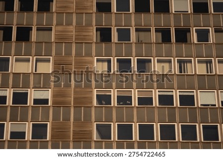 Abstract pattern of apartment building facade with repetitive windows and geometric urban architecture.