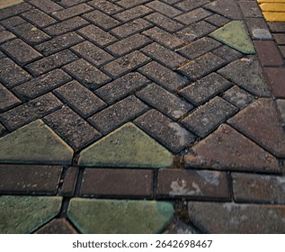 Abstract pattern of dark grey, green, and brown interlocking pavers forming a herringbone and triangle design, suitable for backgrounds or texture overlays.
