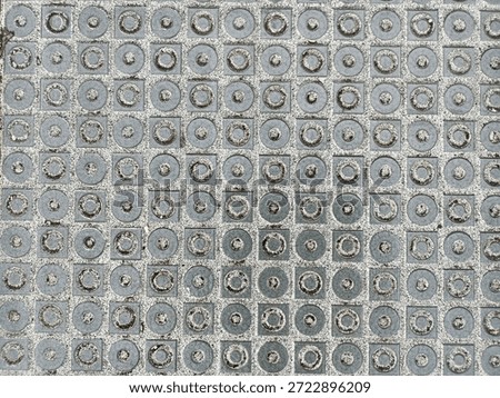 Abstract pattern of squares and nested circles on a textured metallic surface, creating a hypnotic geometric grid