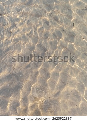 Abstract pattern of sunlight reflecting on clear, shallow sea water over sand. Natural light refractions creating a peaceful and minimal aquatic texture.
