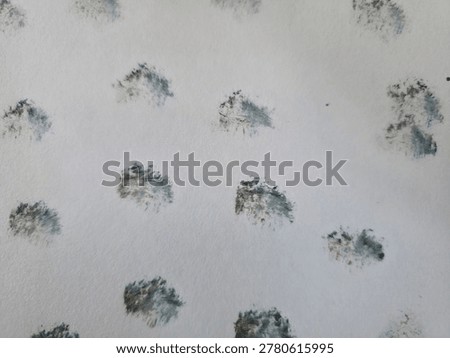 ​An abstract pattern of textured dark grey and blue-green stippled spots arranged on a clean white surface.