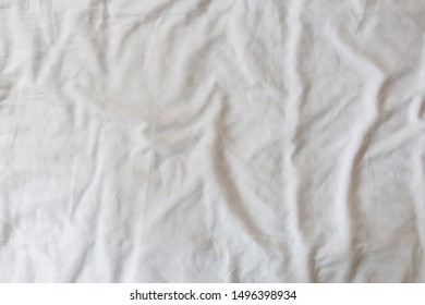 Abstract Pattern Of A White Crumpled Bed Sheet In A Hotel Room. The Manufacturing Of Bedsheet Uses Cotton, Linen, Silk Modal And Bamboo Rayon.