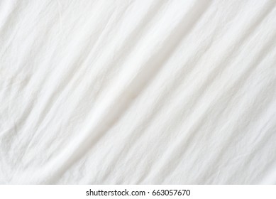 Abstract pattern of a white crumpled bed sheet in a hotel room. 