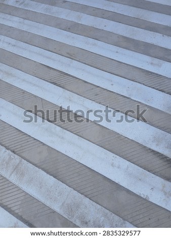 Abstract pattern of white lines on grooved concrete ramp background.