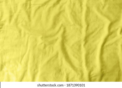 Abstract Pattern Of A Yellow Crumpled Bed Sheet In A Hotel Room. The Manufacturing Of Bedsheet Uses Cotton, Linen, Silk Modal And Bamboo Rayon. Trendy Color Of Year 2021 - Illuminatiing Yellow