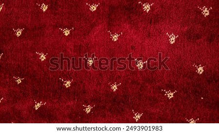 Abstract pattern in yellow or gold on a piece of red carpet