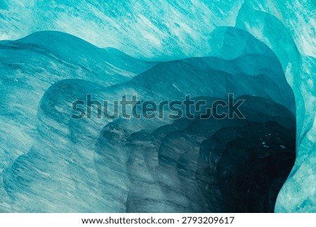 Abstract patterns of blue glacial ice inside the Mer de Glace ice cave near Chamonix Mont Blanc, France. Natural frozen textures, layered ice formations and vibrant turquoise colors created within one of the largest glaciers in the French Alps.