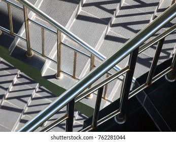 Abstract patterns formed from light and shadow of chrome railings on staircases