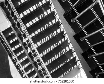 Abstract patterns formed from light and shadow of chrome railings on staircases