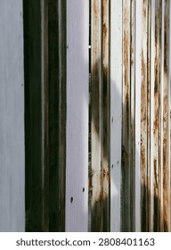 Abstract perspective background of a white rusty metal folding door. Selective focus on vertical steel bars with rust texture, industrial grunge backdrop.