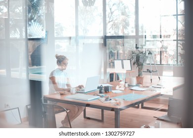Abstraktes Foto einer Frau, die an ihrem Laptop arbeitet, aufgenommen durch das Glas
