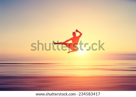 abstract piece of art. man performing flying kick on a blurred surface that looks like a beach at sunset