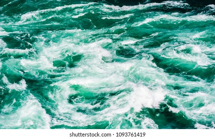Abstract powerful water currents and rapids churning in flowing green river near Niagara Falls, Ontario, Canada.