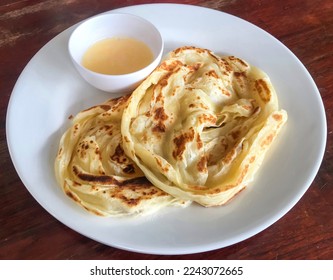 Abstract process photo of Roti canai with a cup of condensed milk as a sweet recipe in Thailand. That also calls roti prata which is an Indian flatbread dish can be cooked sweet or savoury variations - Shutterstock ID 2243072665