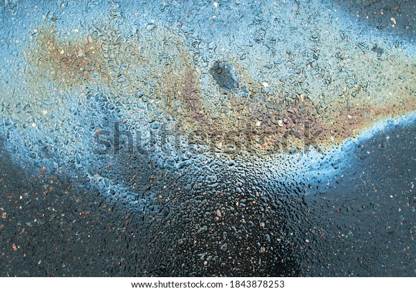 Abstract rainbow effect background, colorful gas\
stain on wet asphalt caused by a leak under a car or\
truck.Environmental pollution\
concept.