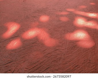 Abstract Red Surface with Light Patterns, This image features a textured red surface illuminated by patches of light, creating a warm and intriguing abstract composition.