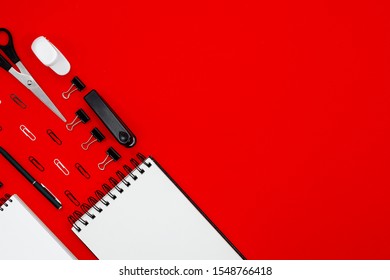 Abstract Red Table With Stationary . Blank Notebook And Scissors, Pensils, Pens. Flatlay Top Horizontal View Copyspace.