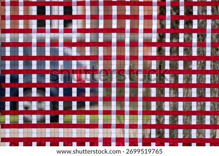 Abstract red and white grid pattern on wire mesh fence, geometric background with symmetry and rhythm in urban environment