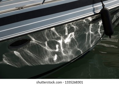 Abstract reflections on the hull of a moored boat.