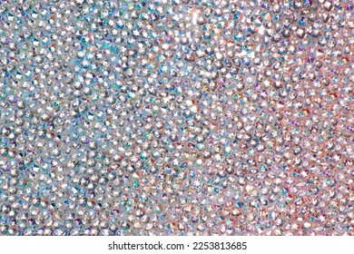 Abstract rhinestones background. Texture of rhinestones illuminated with multi-colored light. Pink and blue shine diamonds. Close up. Flares on glass.