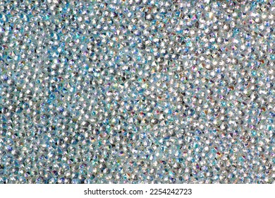 Abstract rhinestones background. Texture of rhinestones illuminated with white light. Multi-colored shine diamonds. Close up. Flares on glass.