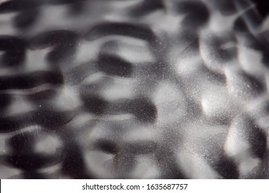 Abstract rippled background texture. Surface of water frozen in time, hi contrast lighting exposes the fascinating patterns created by soundwaves traveling directly through it. 