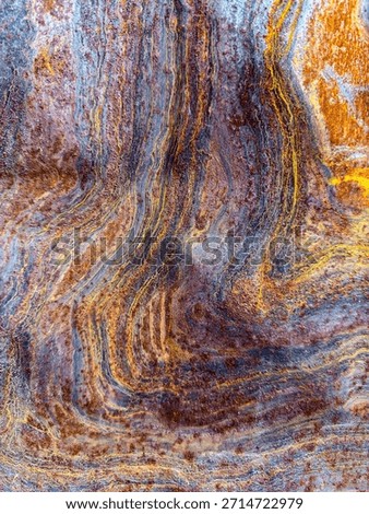 Abstract rusty metal swirl pattern with orange and blue oxidation.