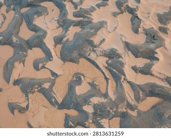 Abstract sand patterns on a beach. Natural textured background of wet dark sand and silt.